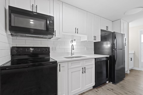 a kitchen with white cabinets and black appliances and a black refrigerator